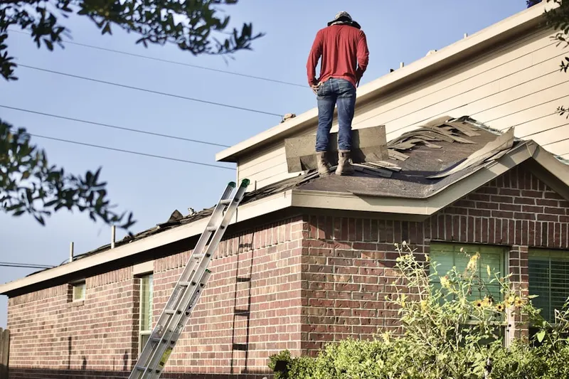 Professional roofer working on a residential roof in Inwood